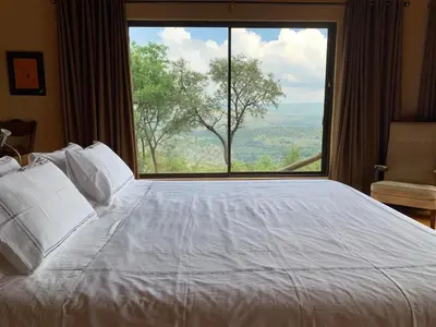 a bedroom with a large bed with a large window at Forestiva Farm - Mountain Retreat in Centurion