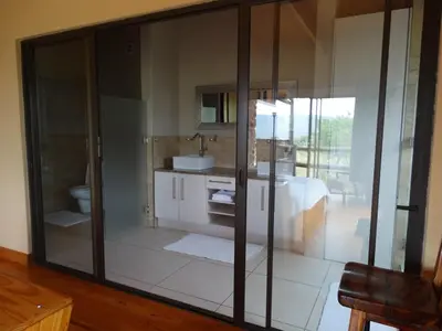 a bathroom with glass walls and a bathroom with a sink at Forestiva Farm - Mountain Retreat in Centurion