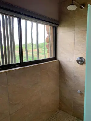 a bathroom with a shower with a window at Forestiva Farm - Mountain Retreat in Centurion