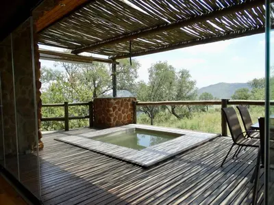 a patio with a hot tub on a wooden deck at Forestiva Farm - Mountain Retreat in Centurion