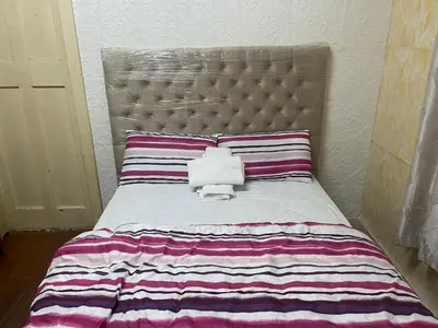 a bed with a striped comforter and a pillow at Cardinal Guest House in Pretoria