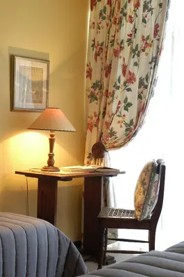 a bedroom with a lamp and a chair and a curtain at Elonda B&B in Pretoria
