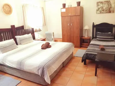 a bedroom with two beds and a dresser in it at Harties Is Africa Safari Lodge in Hartbeespoort