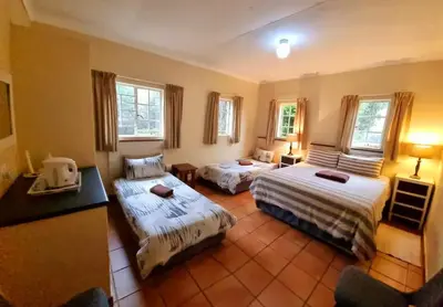 a room with two beds and a table and windows at Harties Is Africa Safari Lodge in Hartbeespoort