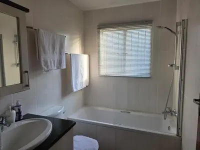 a white bathroom with a tub and a sink at The Urban Dessert 