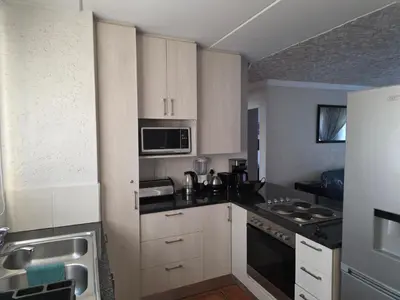 a small kitchen with white cabinets and a sink at The Urban Dessert 