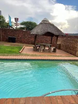 a picnic table with a grass umbrella next to a pool at The Urban Dessert 