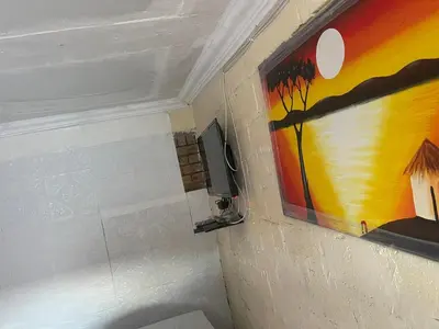a bathroom with a painting and a tv on the wall at Cardinal Guest House in Pretoria