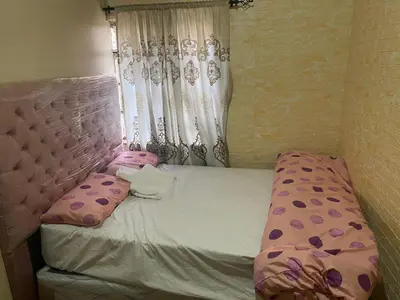 a small bed with pink pillows and a curtain at Cardinal Guest House in Pretoria