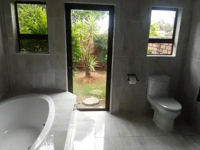 a bathroom with a tub and a toilet and a window at BudiasGuest B&B in Kempton Park
