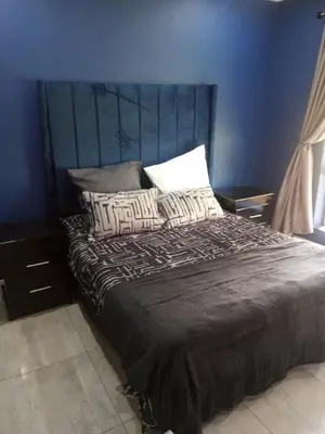 a bedroom with a large bed with a blue wall at BudiasGuest B&B in Kempton Park