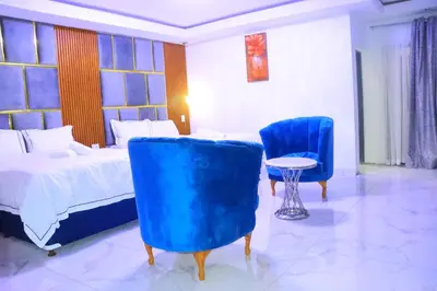 a bedroom with a bed and two blue chairs at Musina Crown Guest House in Musina