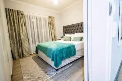 a bedroom with a bed with a green blanket on it at House 22 on Alice in Centurion
