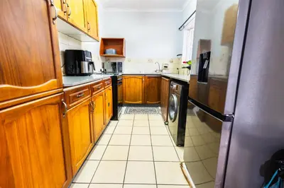 a kitchen with wooden cabinets and a tile floor at House 22 on Alice in Centurion