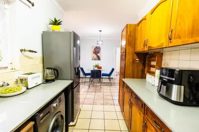 a kitchen with a refrigerator and a table with chairs at House 22 on Alice in Centurion