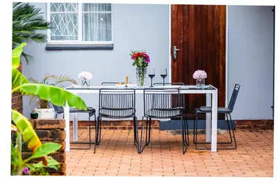 a table with chairs and a vase with flowers on it at House 22 on Alice in Centurion