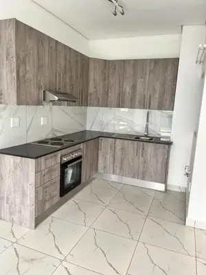 a kitchen with marble counter tops and wooden cabinets at Mphoentle residence in Midrand