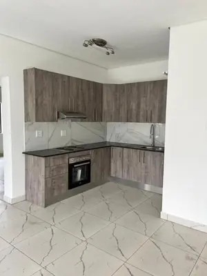 a kitchen with a marble counter top and wooden cabinets at Mphoentle residence in Midrand
