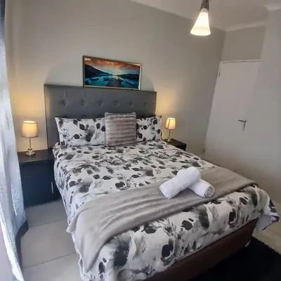 a bedroom with a black and white bed with two towels at The Blyde 1-Bed Luxe Apartment in Pretoria