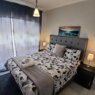 a bedroom with a bed with a black and white comforter at The Blyde 1-Bed Luxe Apartment in Pretoria