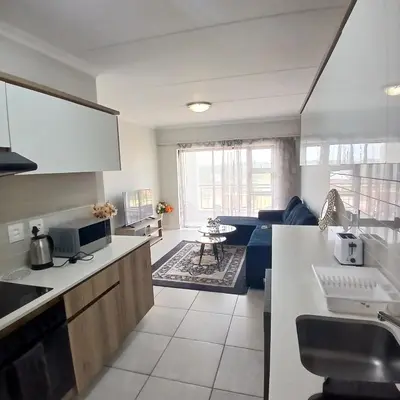 a kitchen and a living room with a couch at The Blyde 1-Bed Luxe Apartment in Pretoria