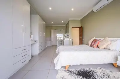 a white bedroom with a bed and a kitchen at Lake Villa Hartebees in Hartbeespoort