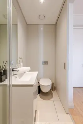 a white bathroom with a toilet and a sink at Cozy Stay at The Ellipse Waterfall in Midrand