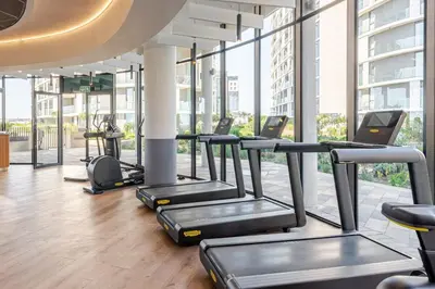 a row of treadmills in a gym with windows at Cozy Stay at The Ellipse Waterfall in Midrand