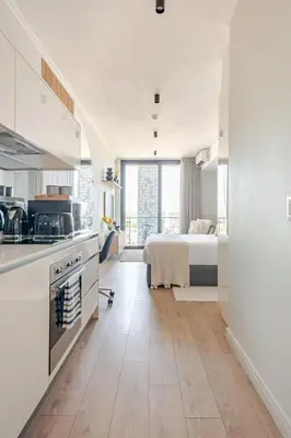 a white kitchen with a bed in a room at Cozy Stay at The Ellipse Waterfall in Midrand