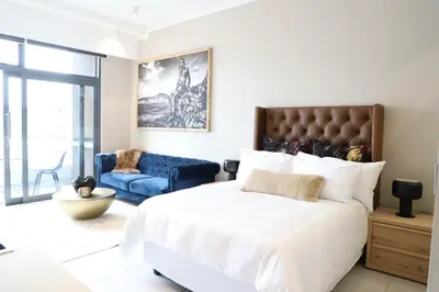 a bedroom with a large bed and a blue couch at 418 menlyn Maine trilogy in Pretoria