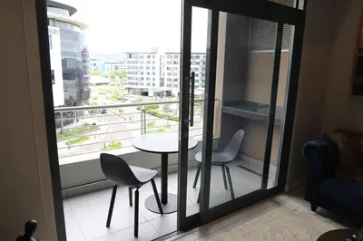 a balcony with a table and two chairs and a window at 418 menlyn Maine trilogy in Pretoria