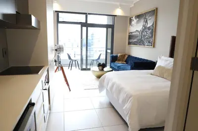 a bedroom with a large bed and a living room at 418 menlyn Maine trilogy in Pretoria