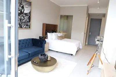 a living room with a bed and a blue couch at 418 menlyn Maine trilogy in Pretoria