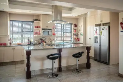 a kitchen with a counter with two stools and a refrigerator at Highland Gate Golf & Trout Estate, House 925 in Dullstroom