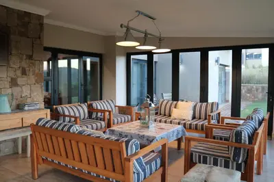 a living room with wooden chairs and a table at Highland Gate Golf & Trout Estate, House 925 in Dullstroom