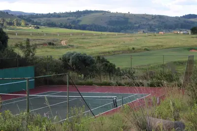 a tennis court in the middle of a field at Highland Gate Golf & Trout Estate, House 925 in Dullstroom