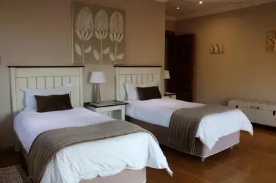 a bedroom with two beds with white sheets at Highland Gate Golf & Trout Estate, House 925 in Dullstroom