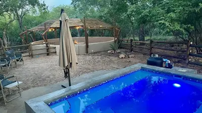 an umbrella next to a swimming pool with a tub at Sounds of Kruger Safari Villa in Marloth Park
