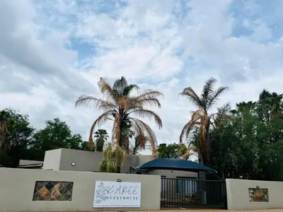 a building with palm trees in the background at Karee Guesthouse in Thabazimbi
