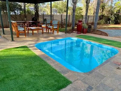 a blue swimming pool in a yard with grass at Karee Guesthouse in Thabazimbi