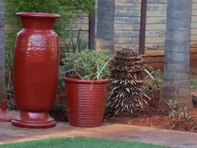 two red vases sitting next to some plants at Karee Guesthouse in Thabazimbi