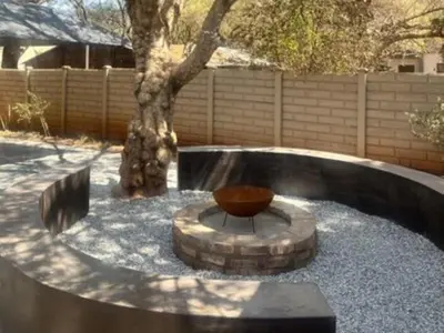a circular seating area with a tree in a yard at Karee Guesthouse in Thabazimbi