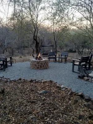a fire pit in the middle of a park with benches at Warthog Corner in Leeupoort