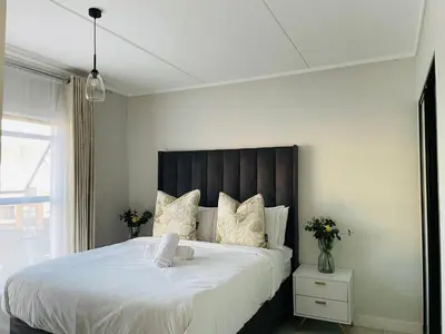 a bedroom with a large bed with a wooden headboard at 2 Bedroom- The Blyde by Given in Pretoria