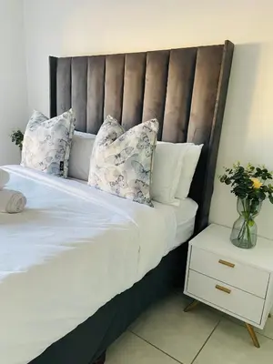 a bed with white sheets and pillows and a vase of flowers at 2 Bedroom- The Blyde by Given in Pretoria