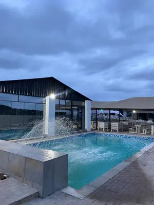 a swimming pool with a fountain in front of a building at Shibar farm house Mpumalanga in eLundi