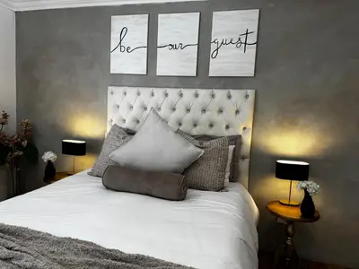 a bedroom with a white bed with three pictures on the wall at Cozy Suburban Escape in Benoni