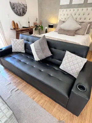 a black leather couch in front of a bed at Cozy Suburban Escape in Benoni