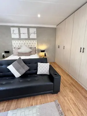 a living room with a black couch and a bed at Cozy Suburban Escape in Benoni
