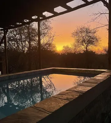 a swimming pool with a sunset in the background at Wabisabi the wild at your doorstep in Marloth Park